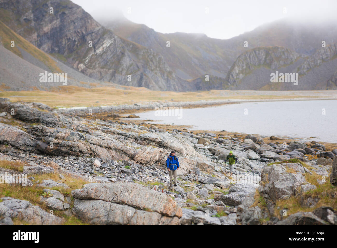 Hikers explore the rocky coast of Vaeroy, Lofoten Islands, Norway. Stock Photo