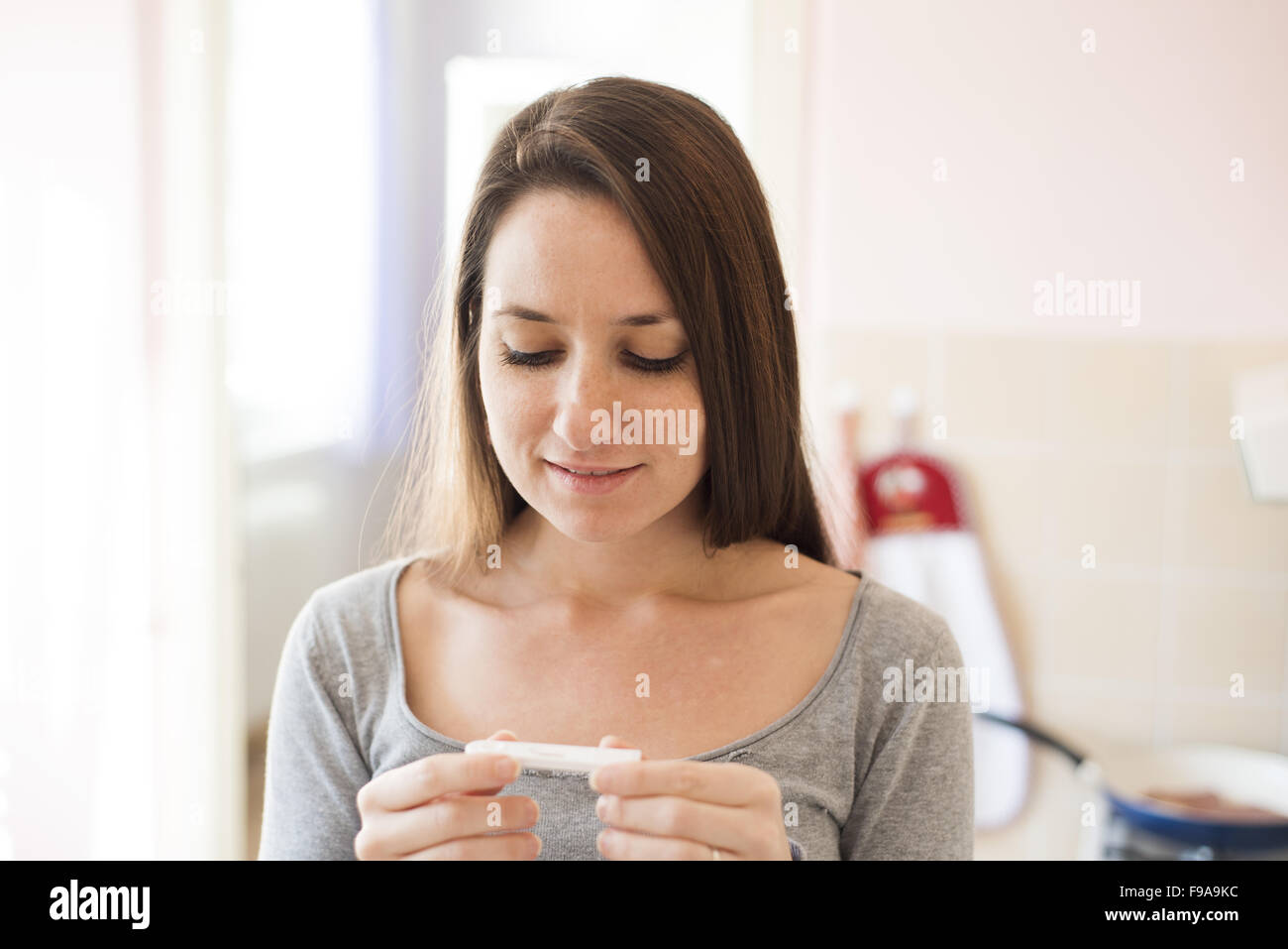 Happy woman with positive pregnancy test result. She is excited at home. Stock Photo