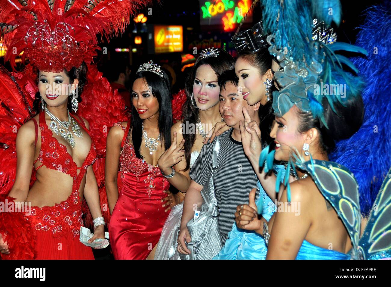Pattaya, Thailand:   An Asian tourist poses with a group of 'ladyboy' performers from the famed Alcazar tranvestite show Stock Photo