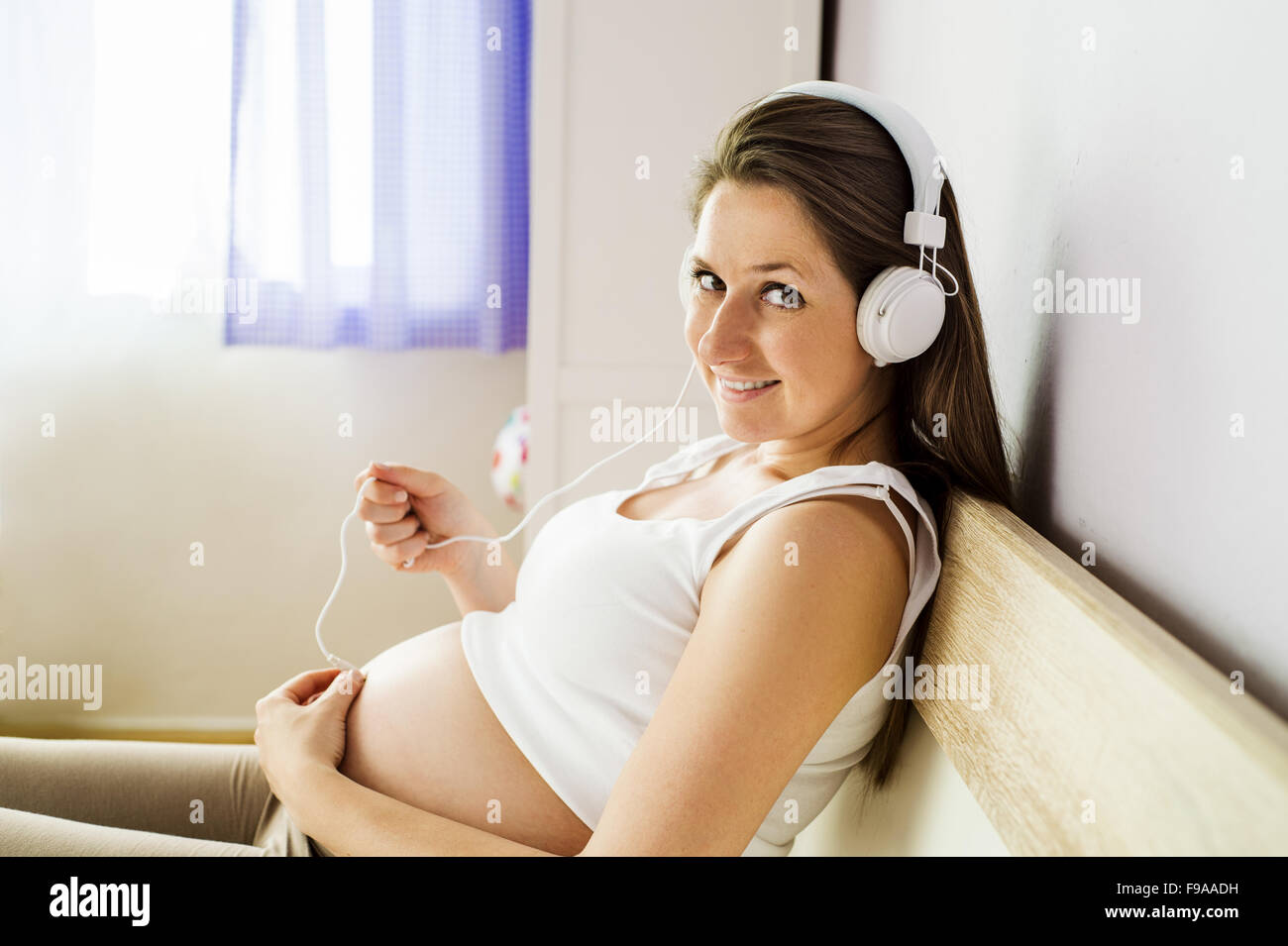 Pregnant woman music lover put the headphones on her belly to let Rebecca  enjoy the music she likes. Girl waiting for a baby keeps headphones on her  Stock Photo - Alamy