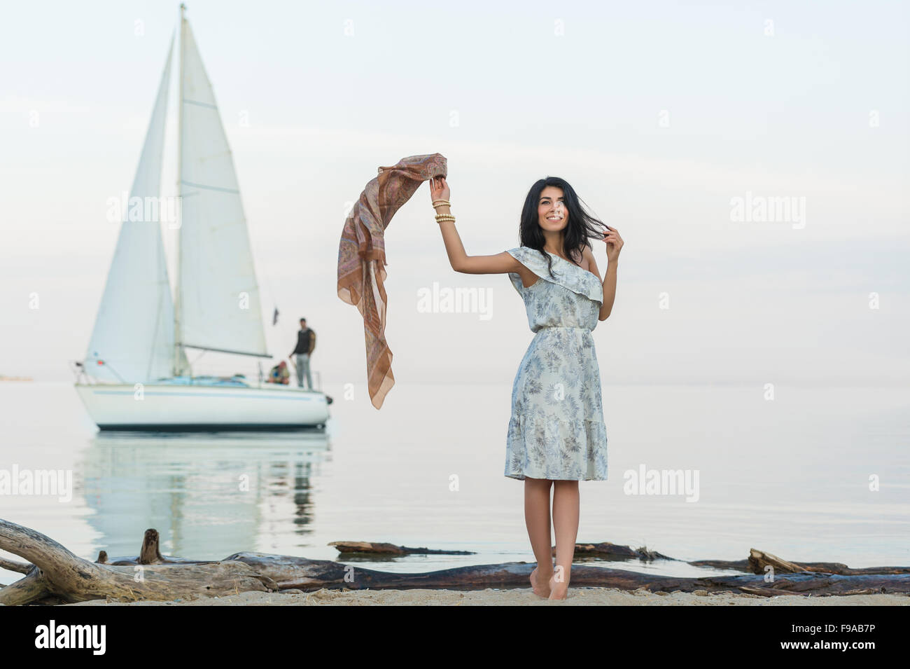 Free woman enjoying freedom feeling happy at beach at morning. Beautiful serene woman and welcoming yacht and sailor with arms o Stock Photo