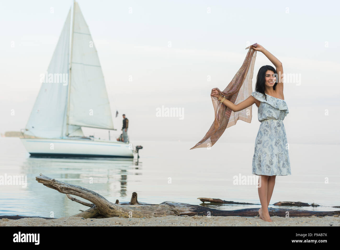 Free woman enjoying freedom feeling happy at beach at morning. Beautiful serene woman and welcoming yacht and sailor with arms o Stock Photo