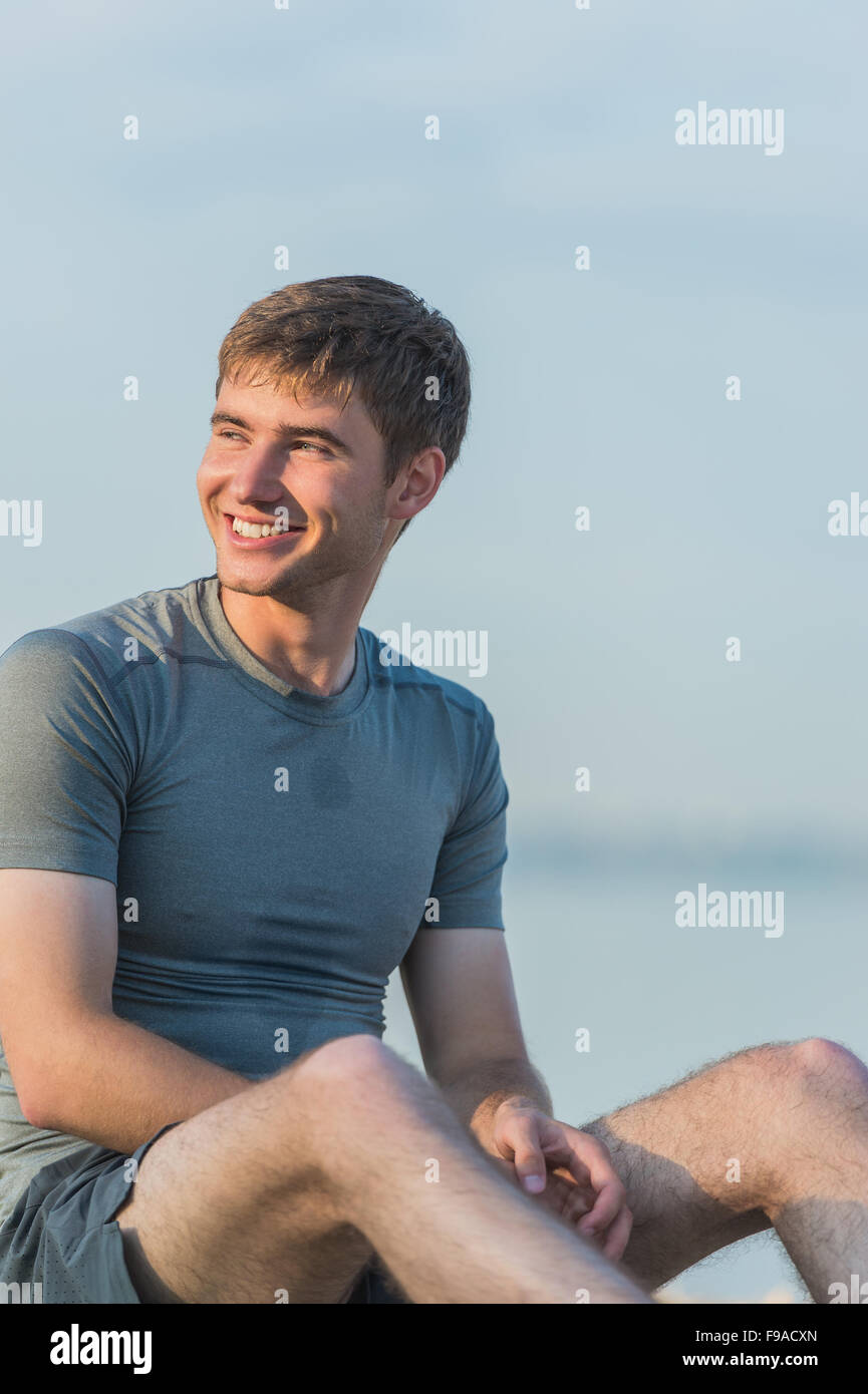 Sporty man resting after workout on beach during sunset Stock Photo