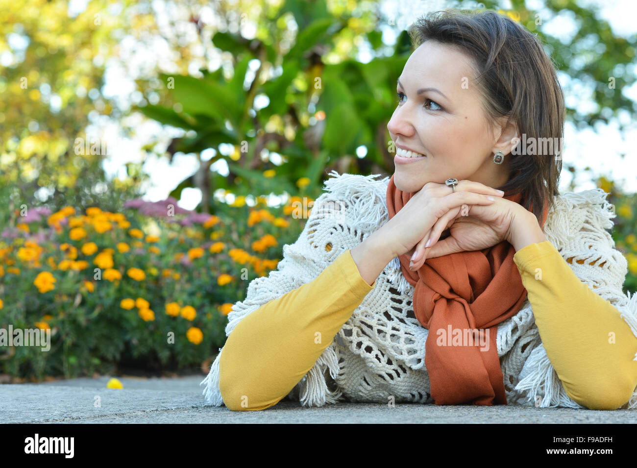 smiling woman sitting outdoors in autumn Stock Photo