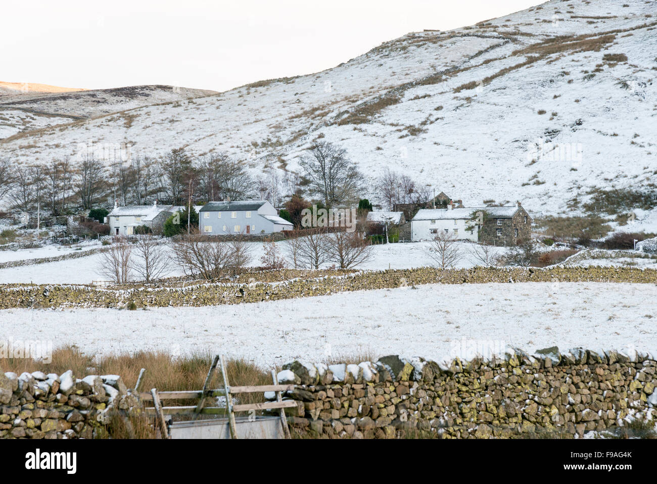 A snowy landscape of Cumbrian farms, buildings and mountains near