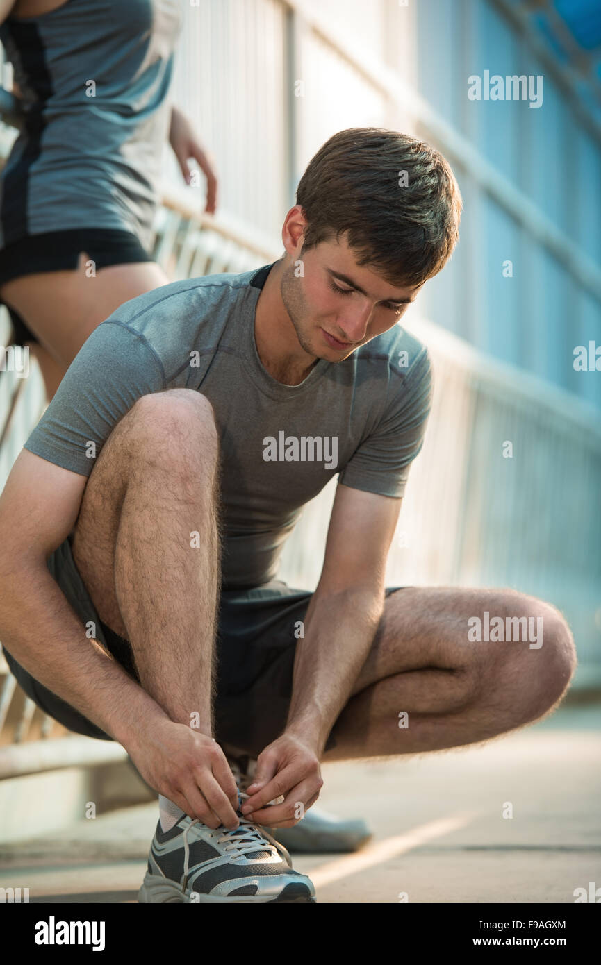 Handsome man lacing his shoes before running outdoors Stock Photo