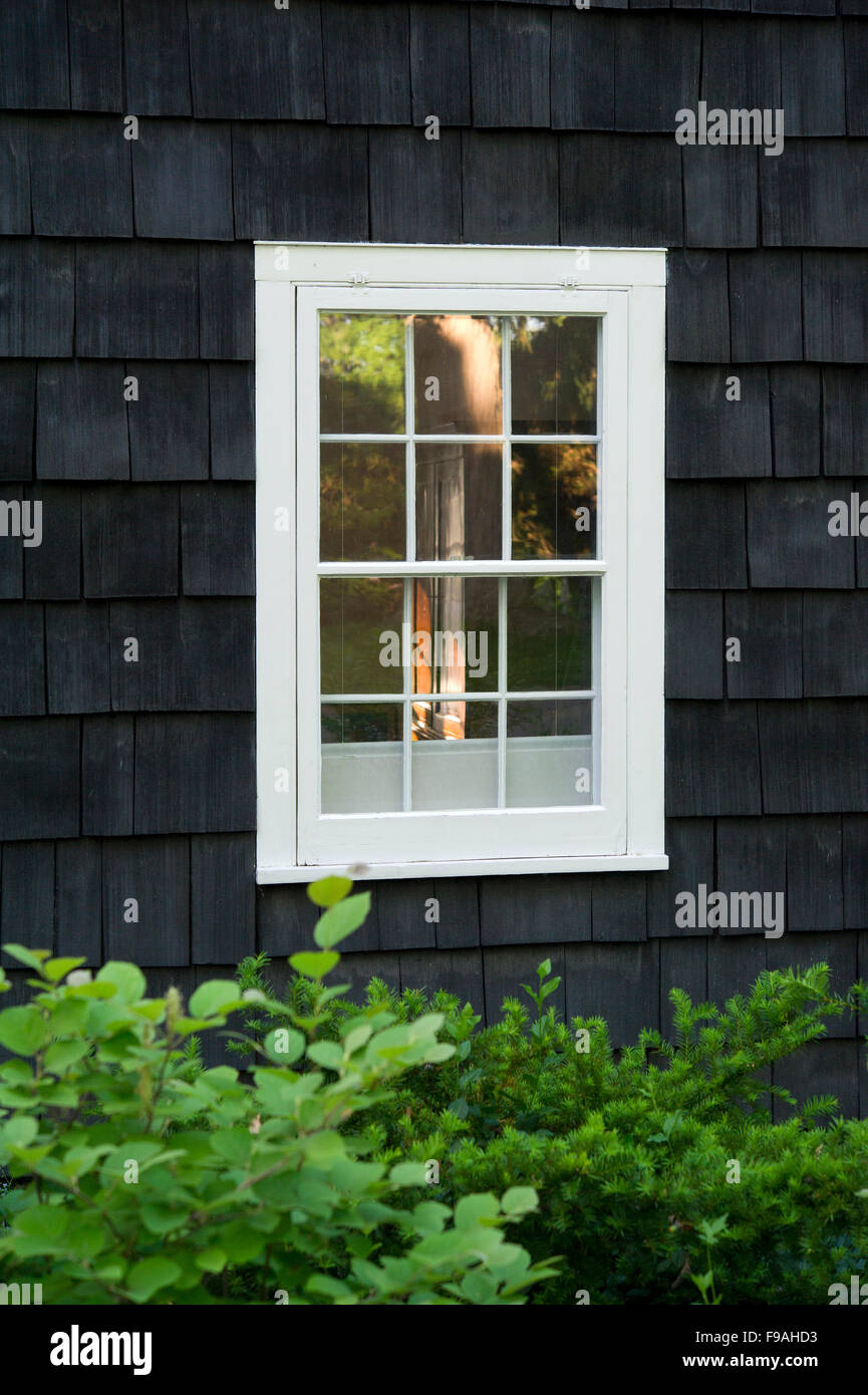 Traditional window with white frame on black wooden shingles wall Stock Photo
