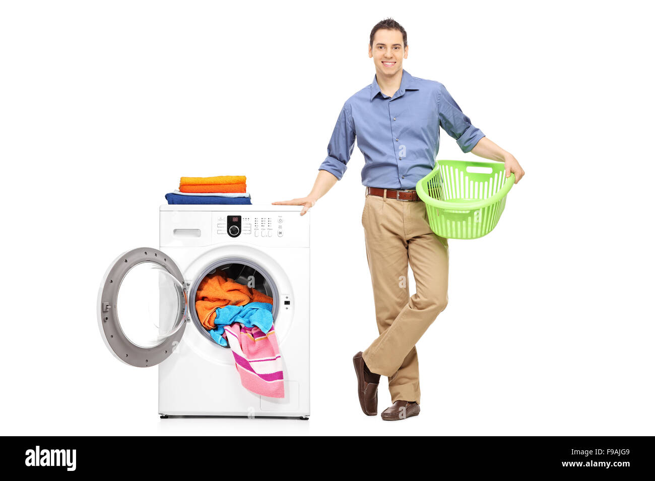 Full length portrait of a cheerful young man holding an empty laundry basket and standing next to a washing machine Stock Photo