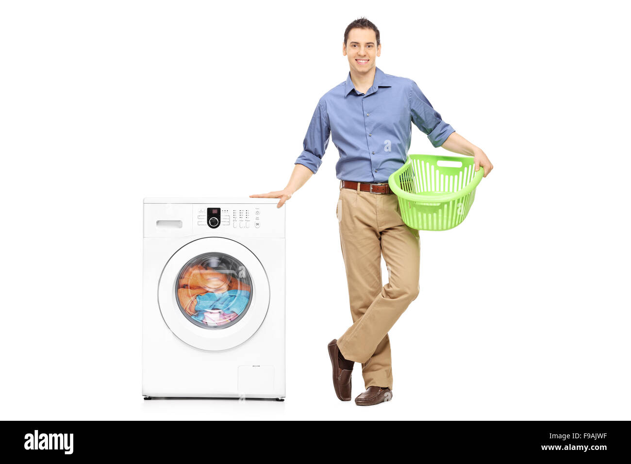 Full length portrait of a young guy holding an empty laundry basket and waiting for the washing machine to finish Stock Photo