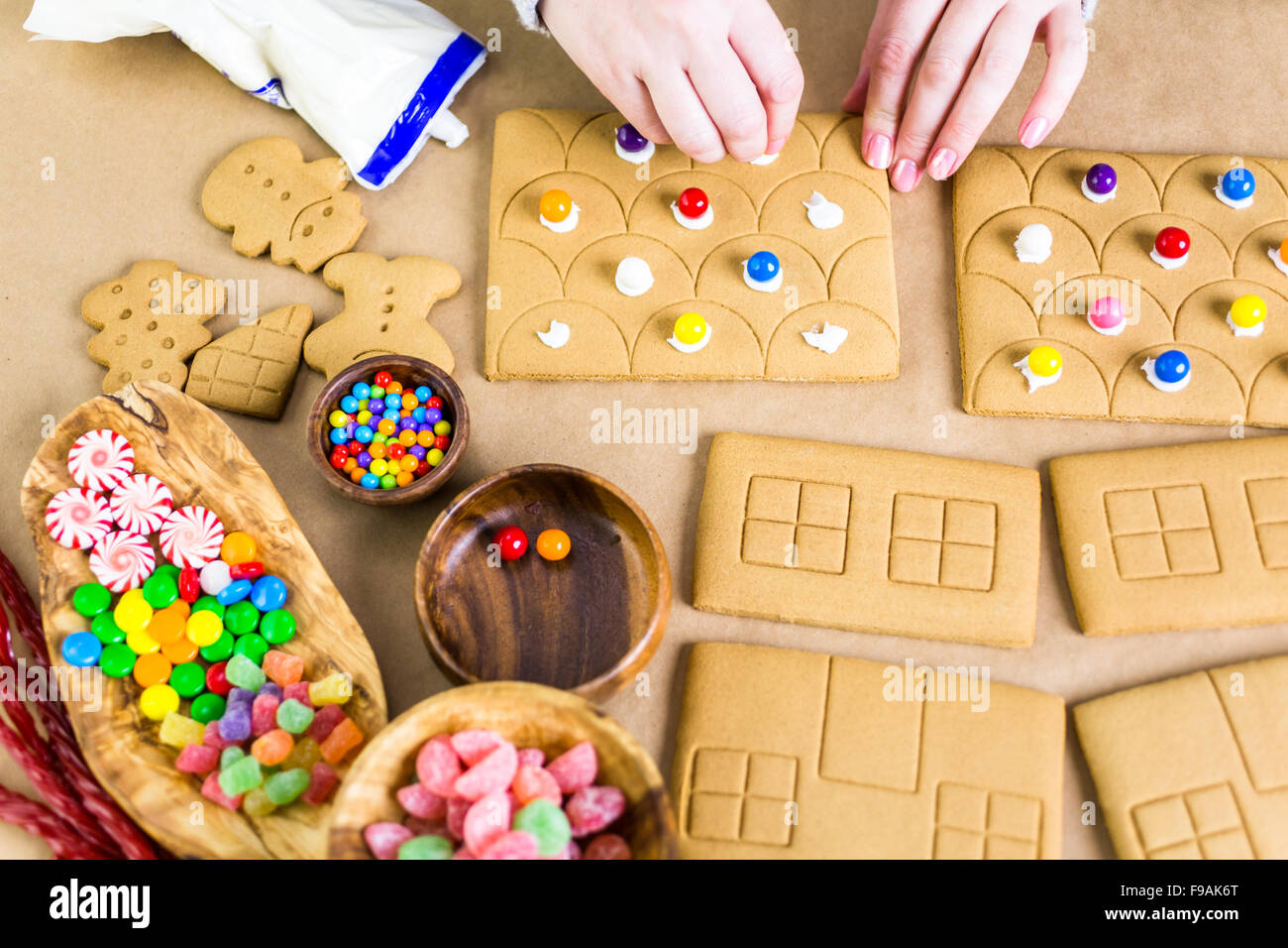 Decorating gingerbread house with royal icing and colorful candies ...