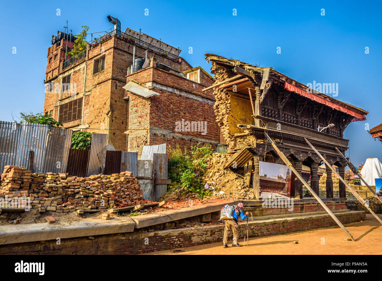 Old man walks around a building destroyed by earthquake Stock Photo