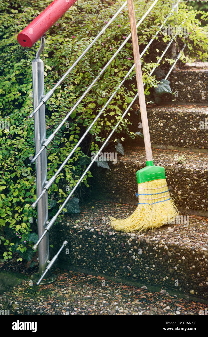 straw broom standing outside on stairs Stock Photo