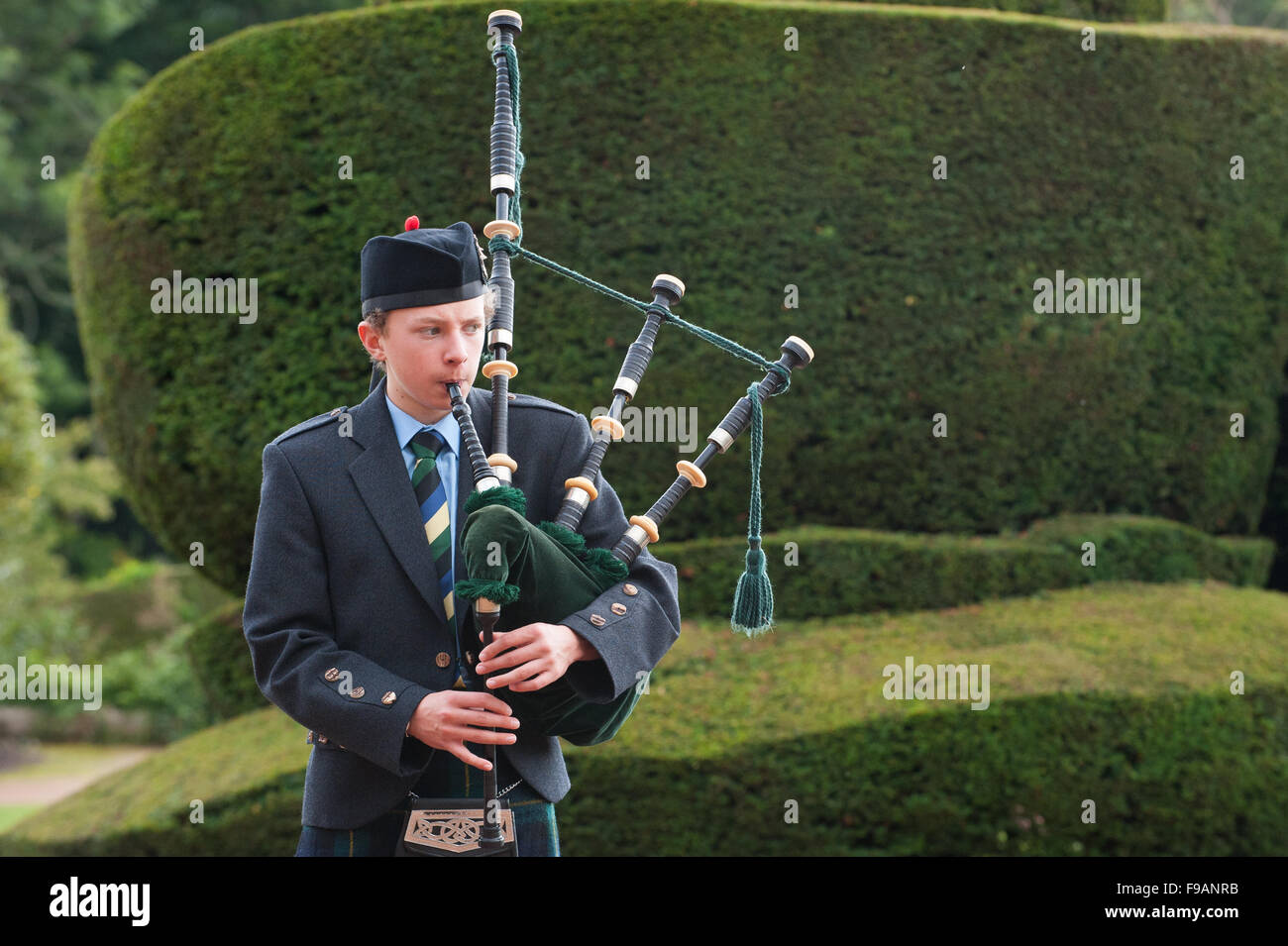 Teen boy playing bagpipes outside Crathes Castle in Aberdeenshire