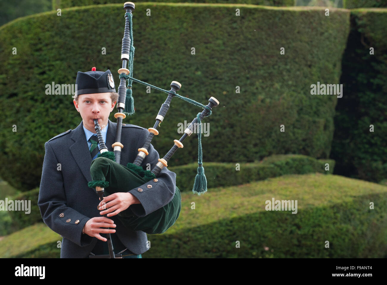 Teen boy playing bagpipes outside Crathes Castle in Aberdeenshire