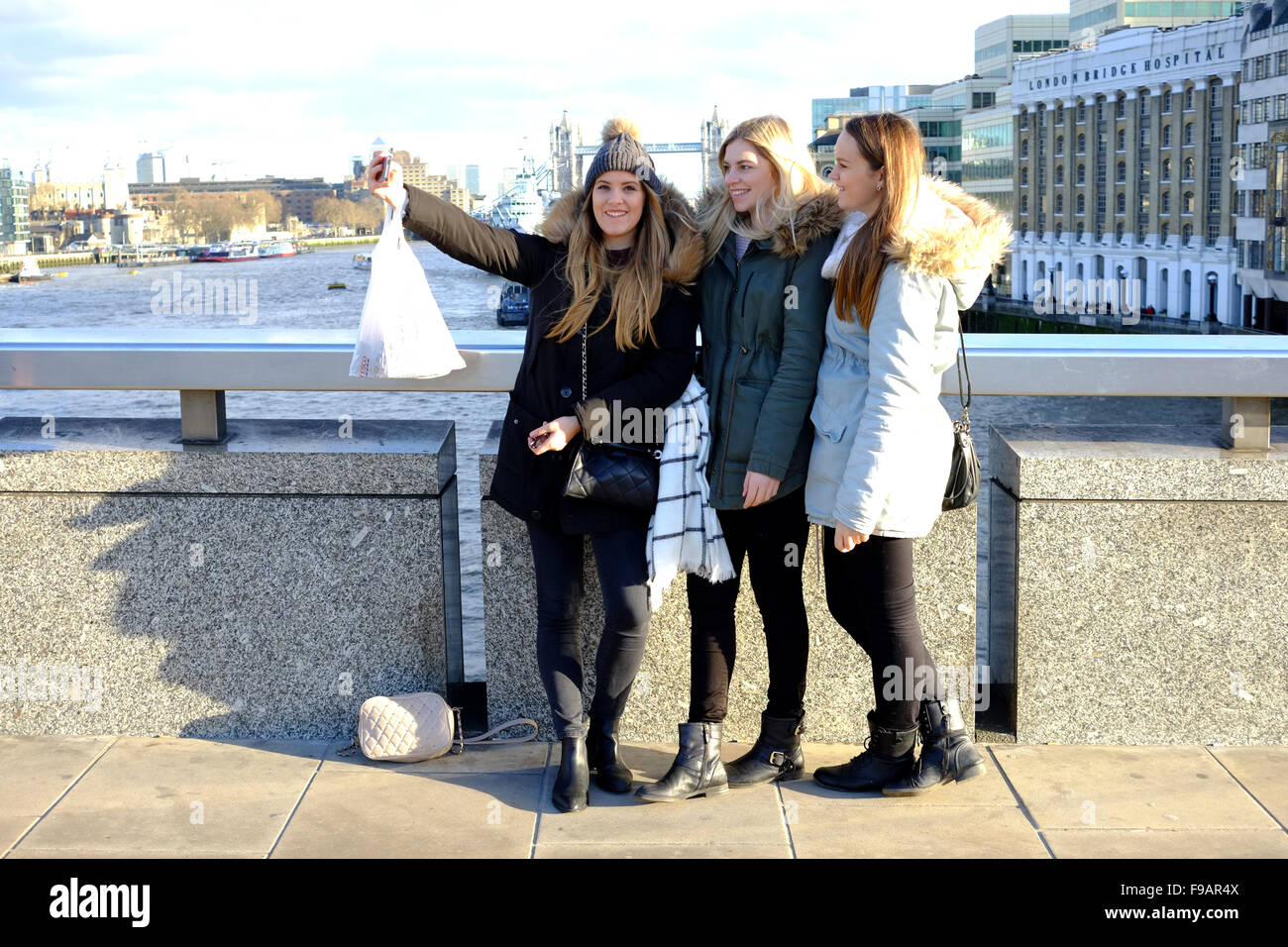 Street photography in London - friends taking a group selfie on London Bridge spot the photographer Stock Photo
