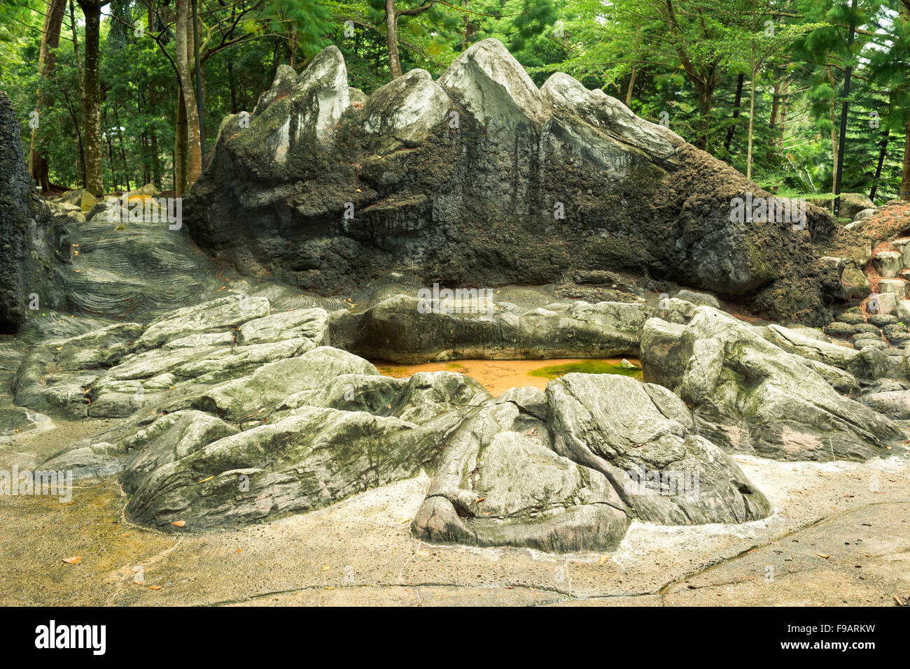 prehistoric artificial landscape with scenic stone cliffs and small pond in Singapore Botanical garden Stock Photo