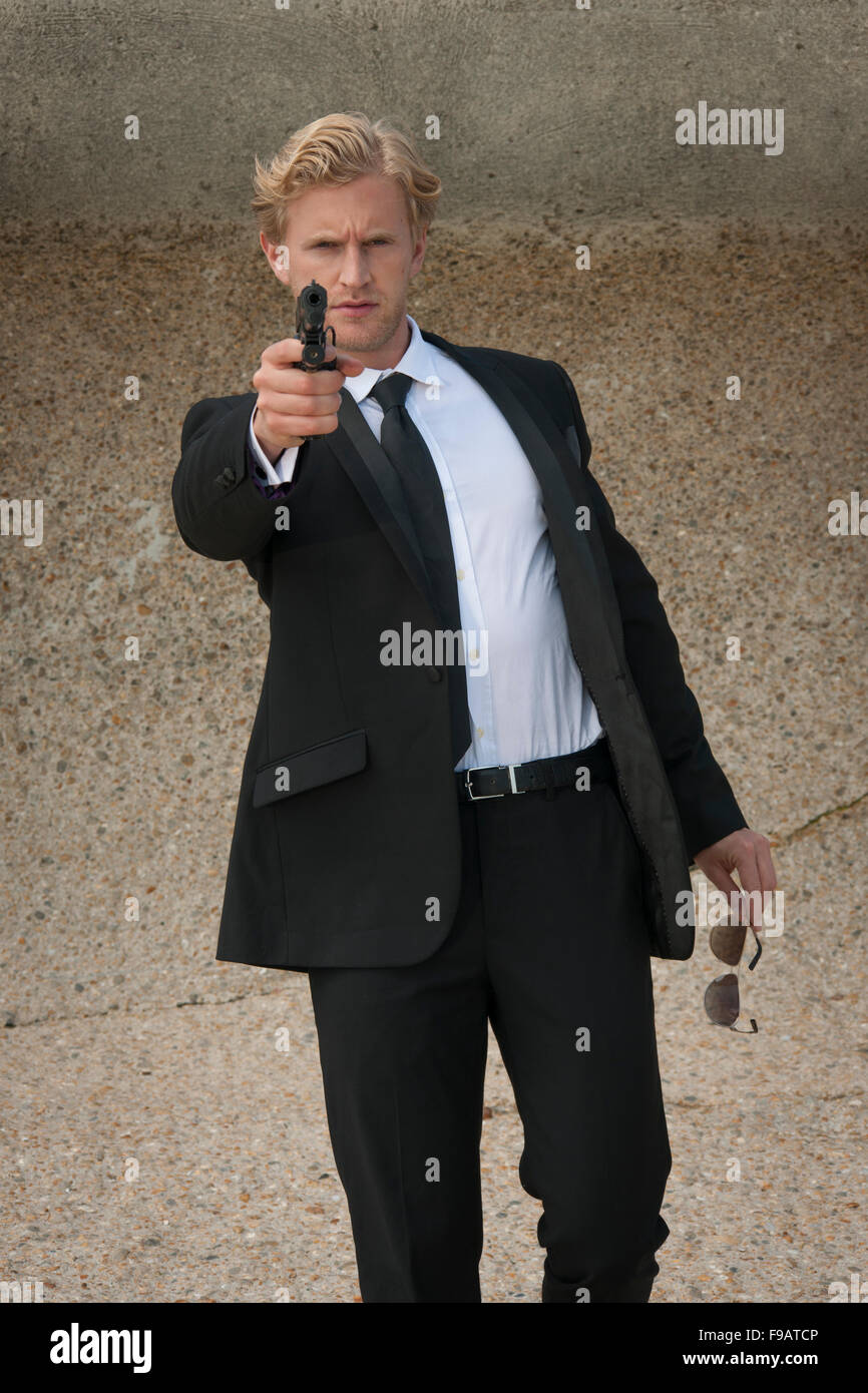 man holding a hand gun, aiming towards the camera Stock Photo
