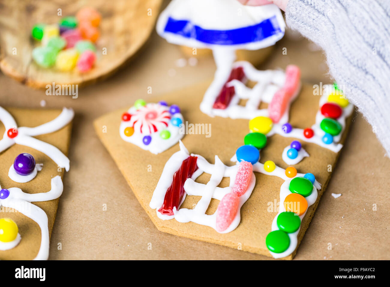 Decorating gingerbread house with royal icing and colorful candies ...