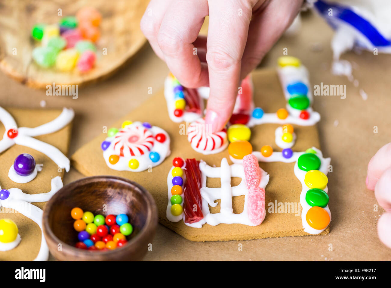 Decorating gingerbread house with royal icing and colorful candies ...