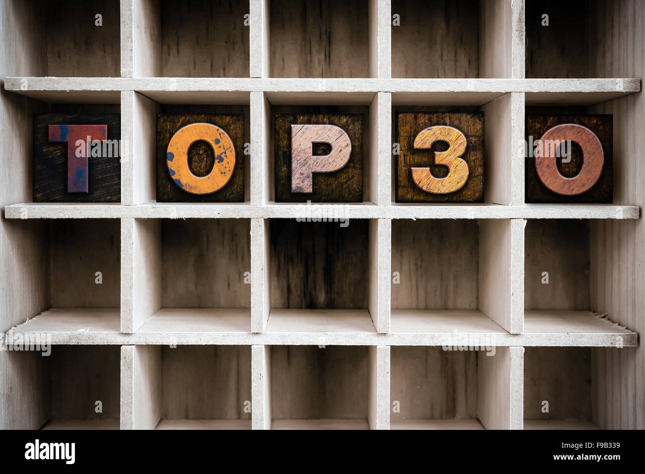 The word "TOP 30" written in vintage ink stained wooden letterpress type in a partitioned printer's drawer. Stock Photo