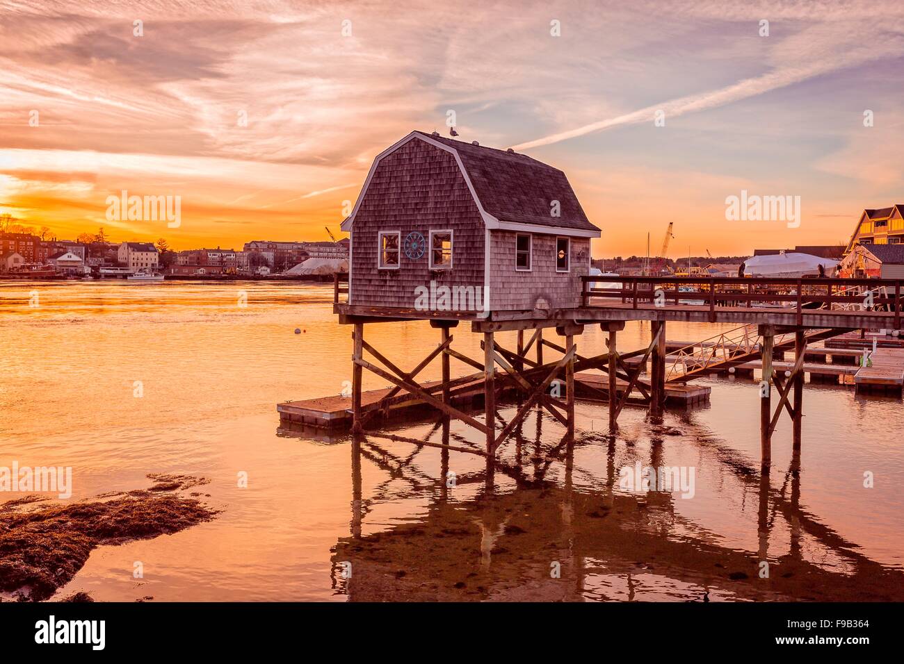 Setting sun over the lobster docks of Kittery Maine look across the harbor towards Portsmouth, New Hampshire. Stock Photo