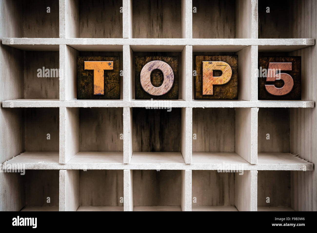 The word "TOP 5" written in vintage ink stained wooden letterpress type in a partitioned printer's drawer. Stock Photo