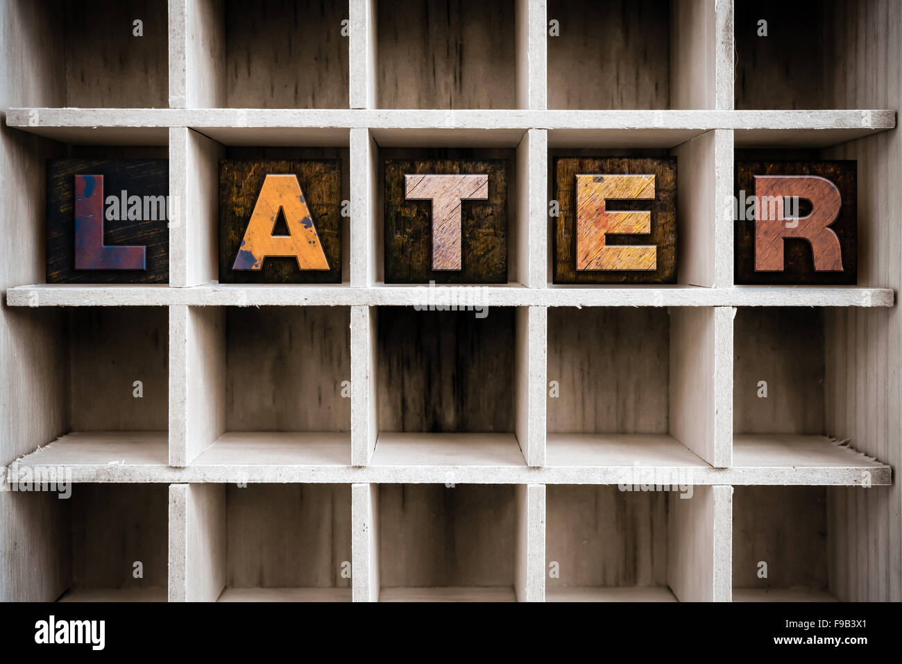 The word "LATER" written in vintage ink stained wooden letterpress type in a partitioned printer's drawer. Stock Photo