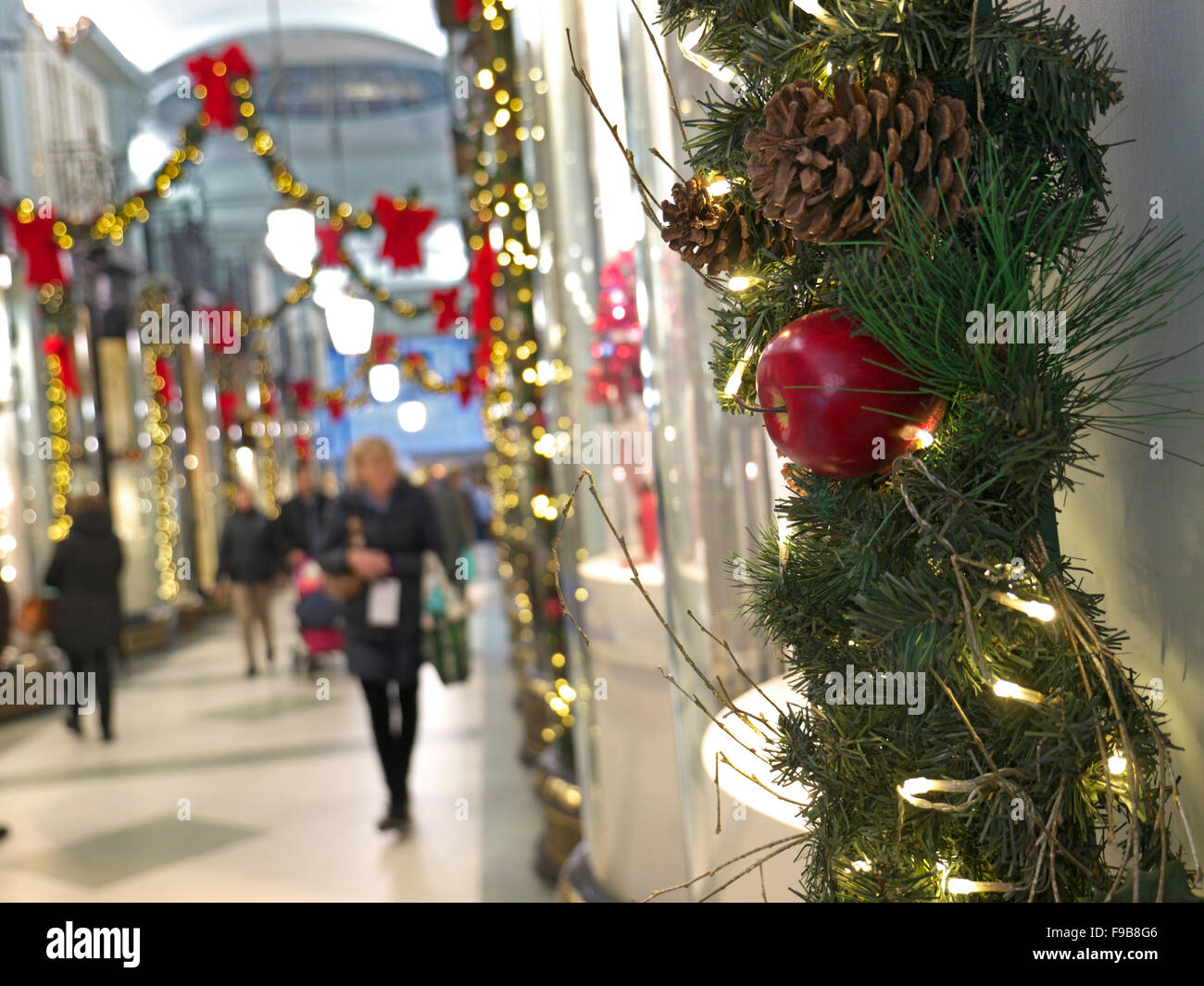 CHRISTMAS SHOPPING SHOPPERS The Piccadilly Arcade with Christmas decorations and shoppers in b/g Piccadilly  London UK Stock Photo