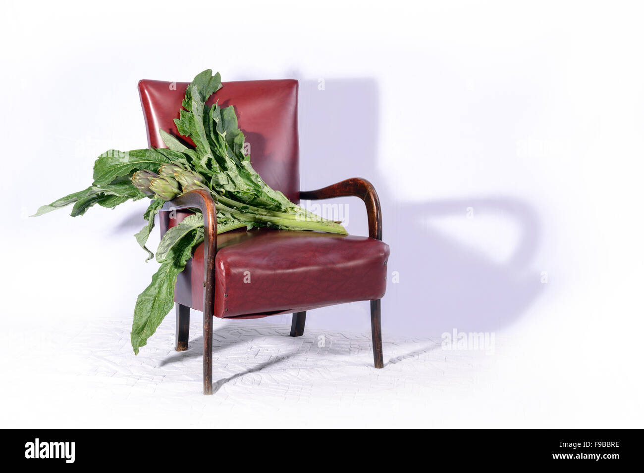 A nice four  artichokes with broad leaves resting on the kitchen chair before being cooked. Stock Photo