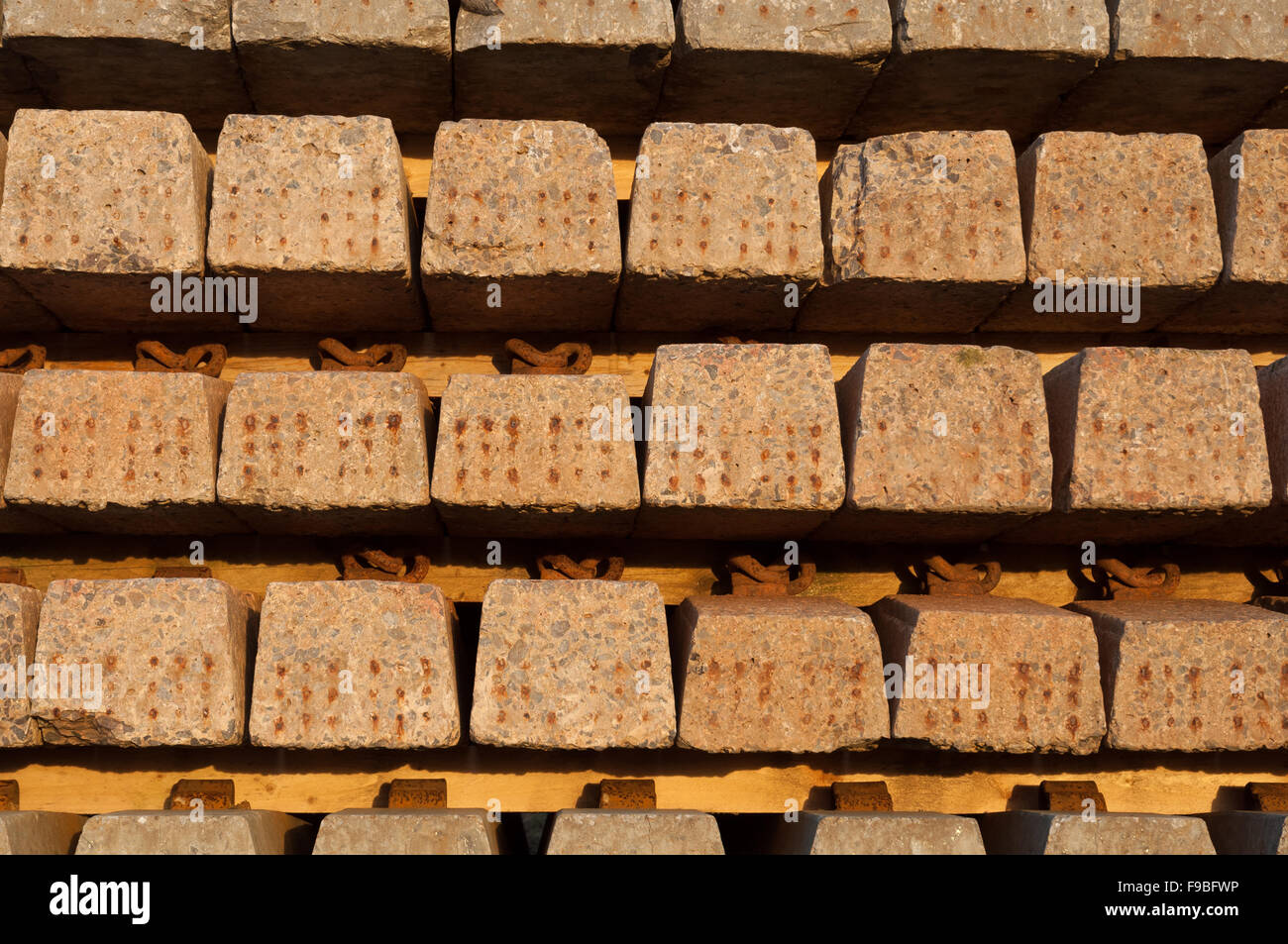 Stack of reinforced concrete railway sleepers in golden light of late afternoon sun on winter. Stock Photo