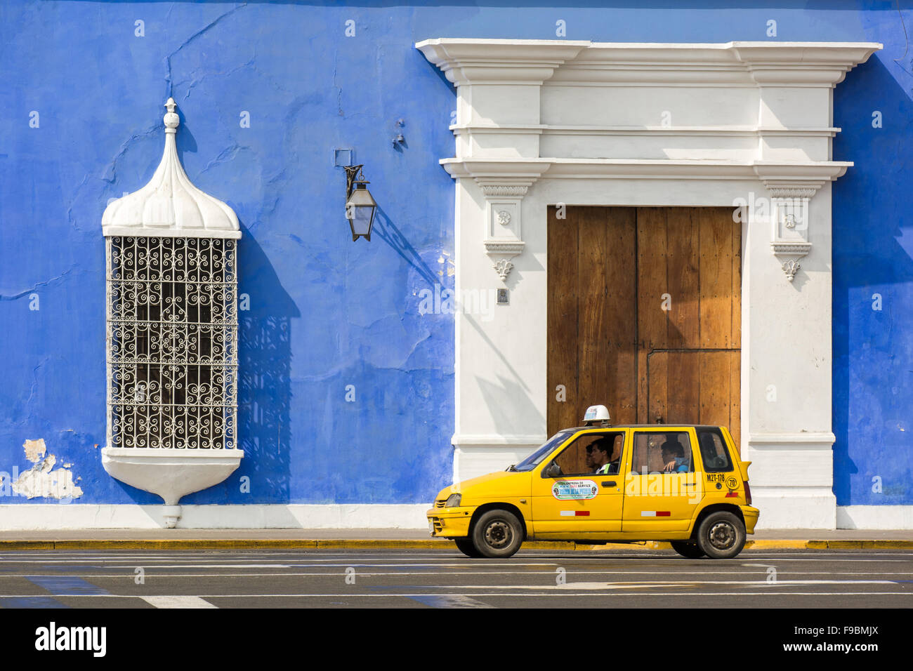 Typical small yellow taxi against colonial style building in main square of Trujillo city in northern Peru Stock Photo
