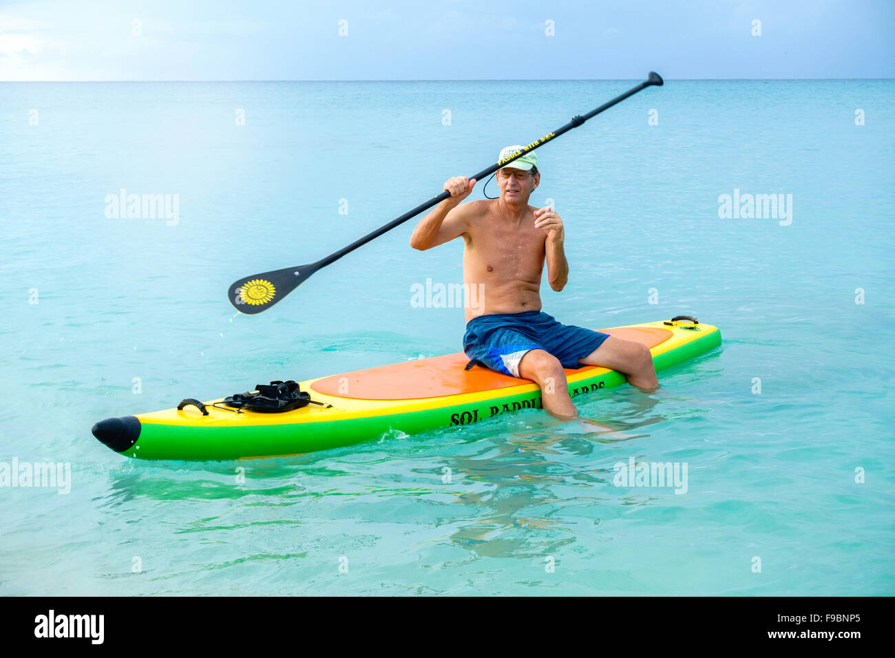 A 60 Year Old Caucasian Man Sits On His Inflatable Paddleboard And a-60-year-old-caucasian-man-sits-on-his-inflatable-paddleboard-and