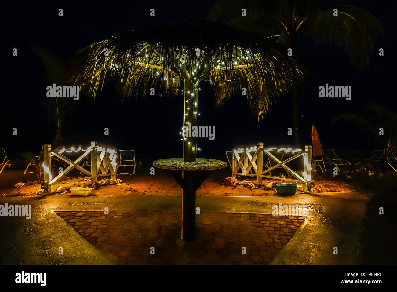 A palapa and fence leading to the beach are lit up with sparkly white lights at night on a beach resort on St. Croix, U.S. Virgin Islands. Stock Photo
