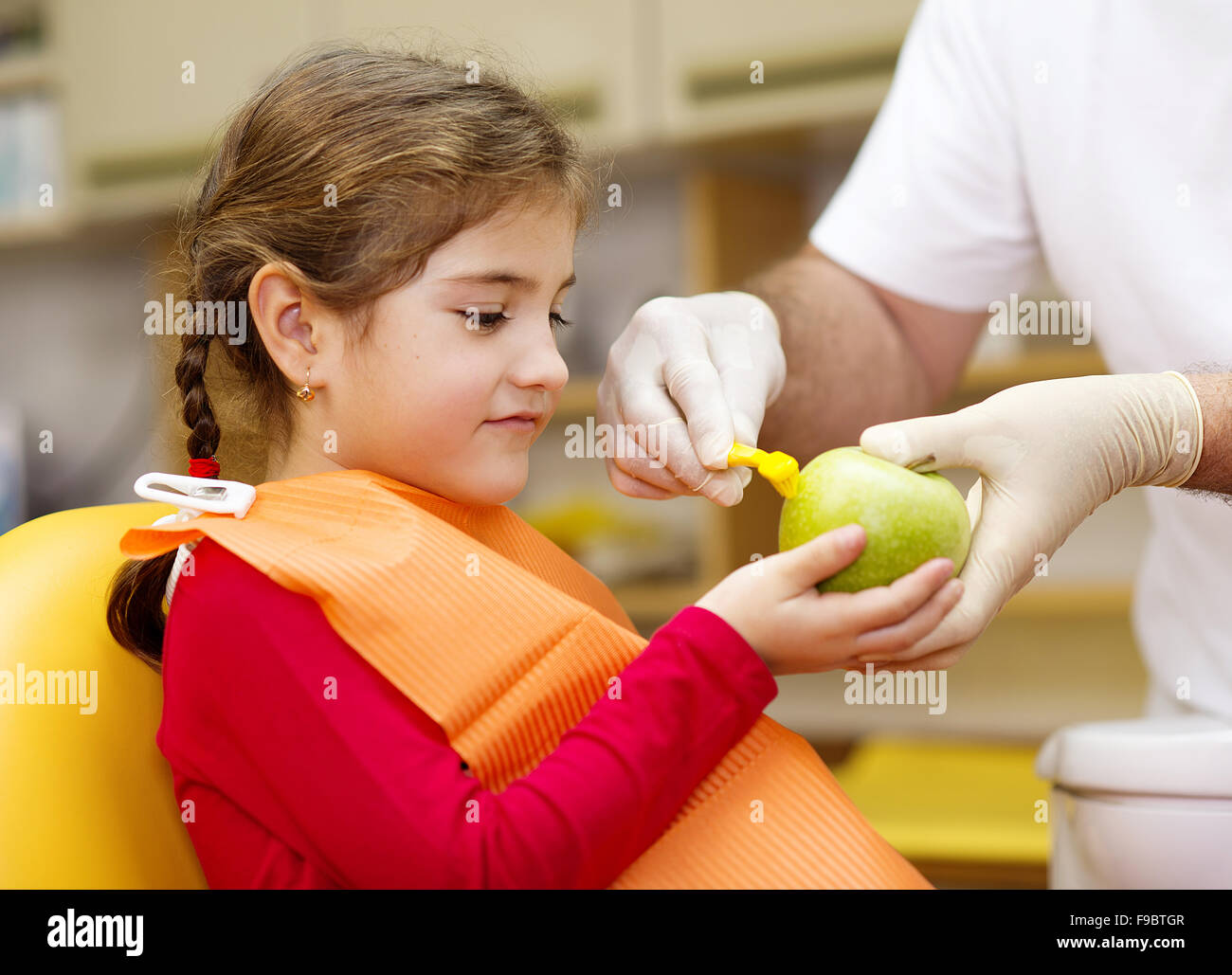 Dentist is showing the technique of teeth cleaning to a little girl