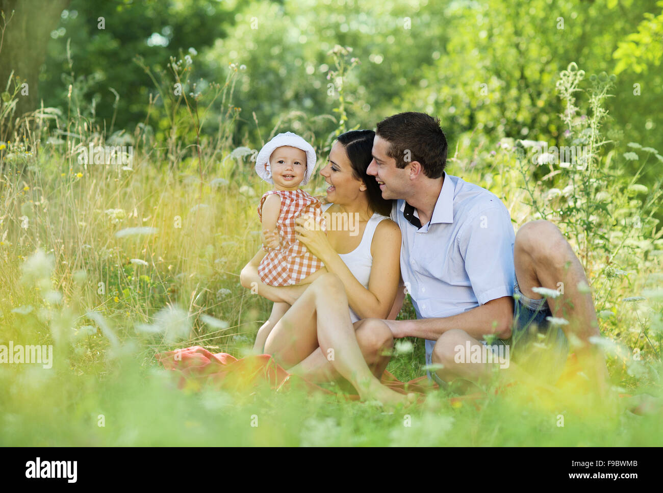 Happy young family spending time together in green nature. Stock Photo