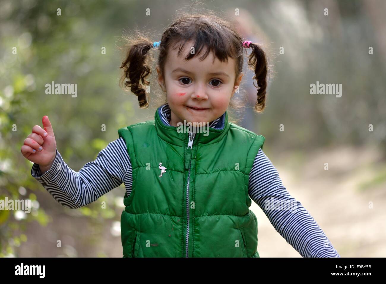 Girl with pigtails running in parkland, with pen on face Stock Photo