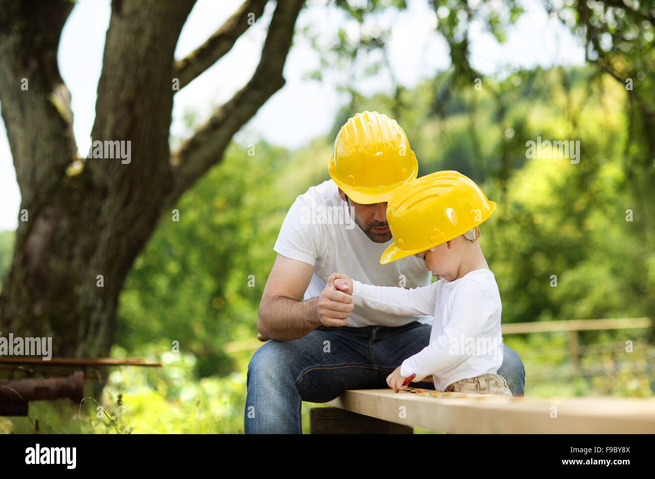 Little son helping his father with building work Stock Photo