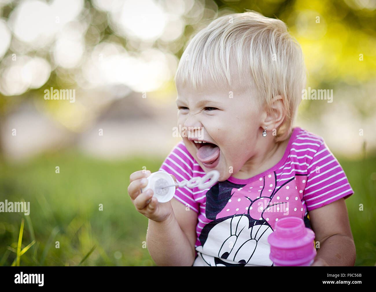 Happy little girl is playing in the green sunny park Stock Photo - Alamy