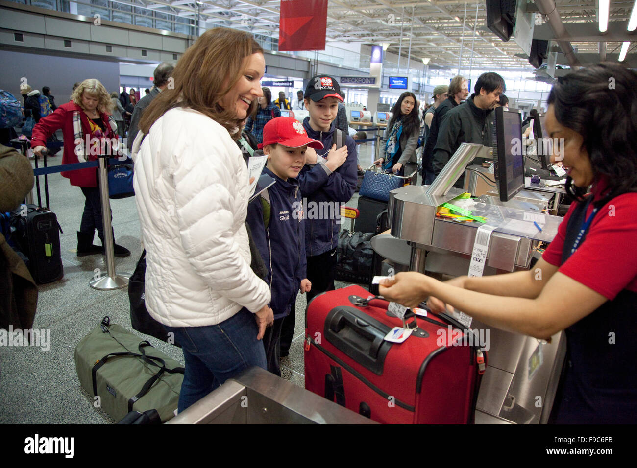 Mom And Two Sons Watch Delta Ticket Agent Attach ID Tag On Luggage At 