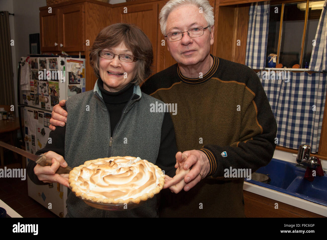 American Gothic style photo of spouses holding a meringue topped pie in their kitchen. St Paul Minnesota MN USA Stock Photo