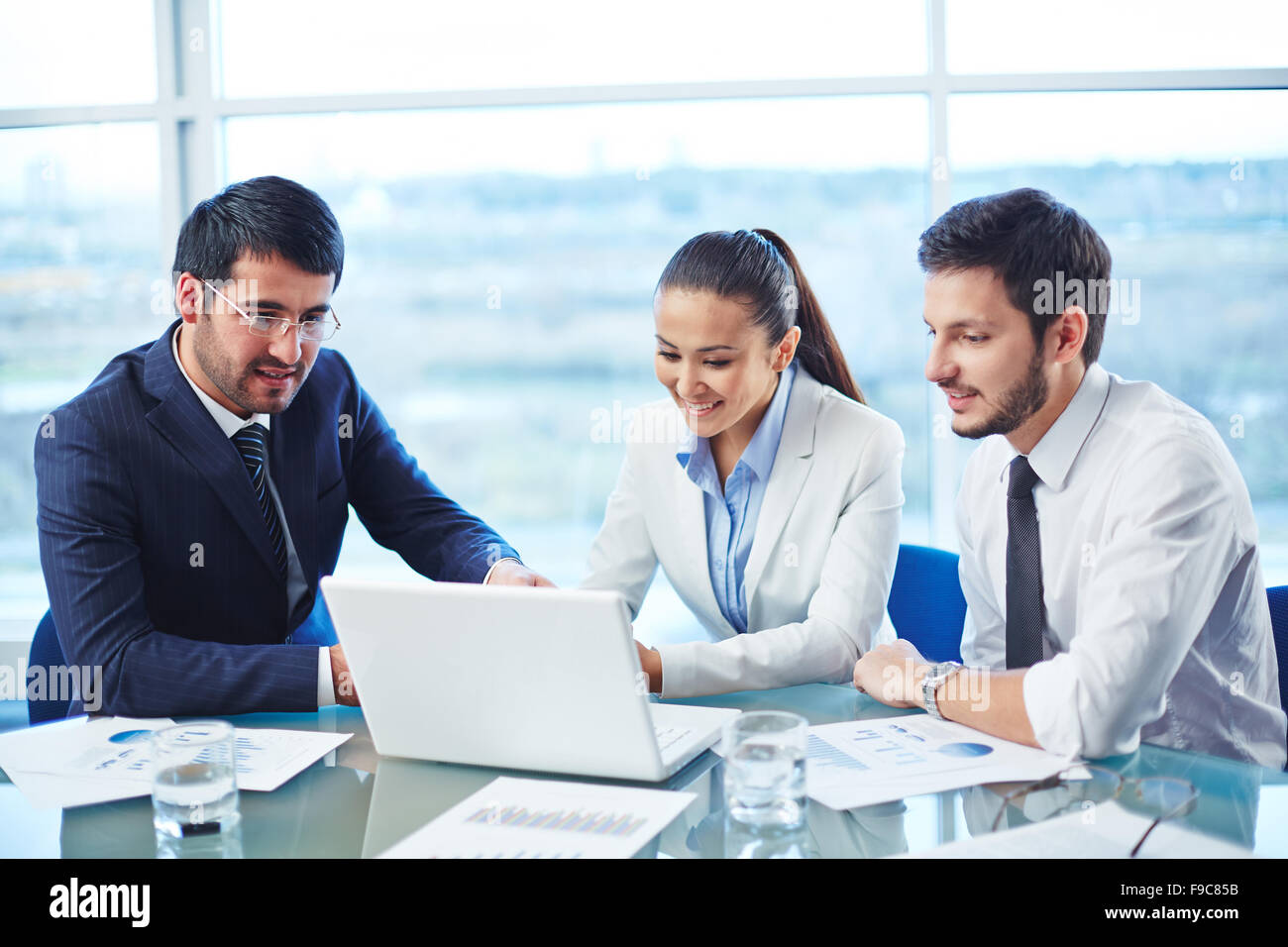 Businessman showing the presentation on computer to his colleagues ...