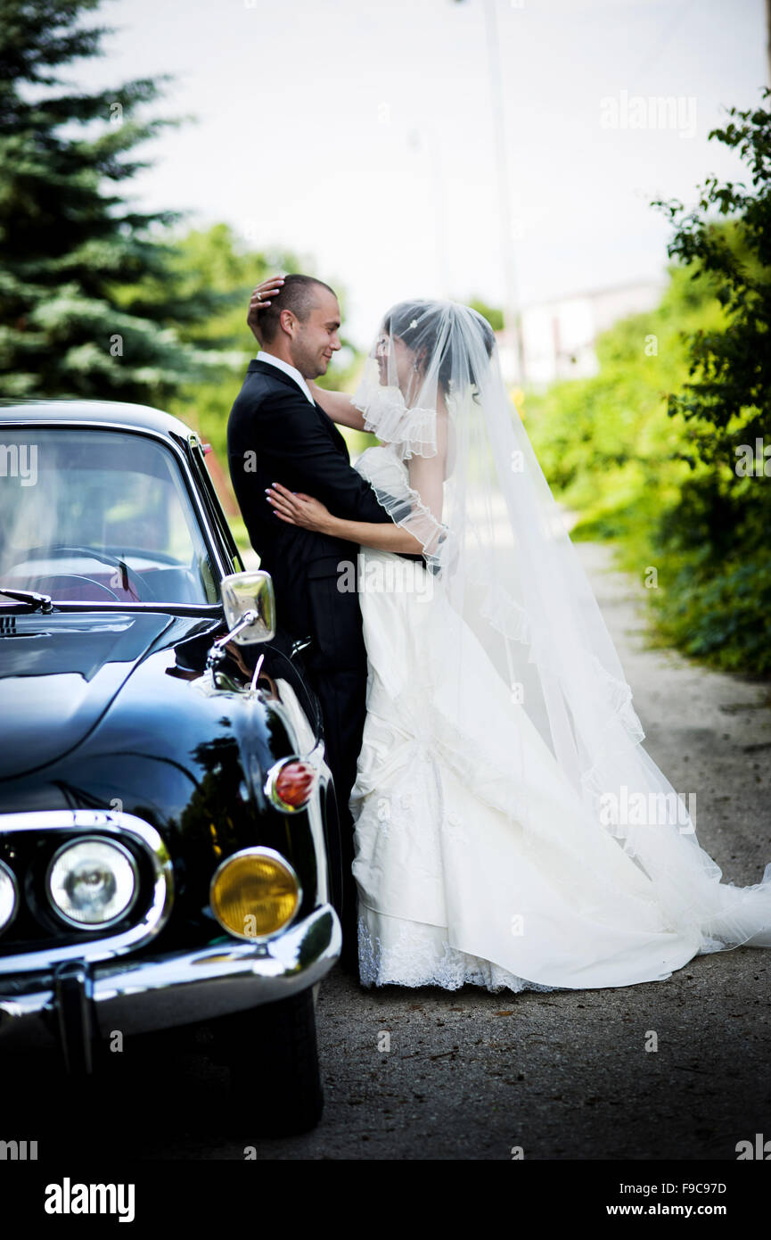 Happy bride and groom in a black car on wedding day Stock Photo - Alamy