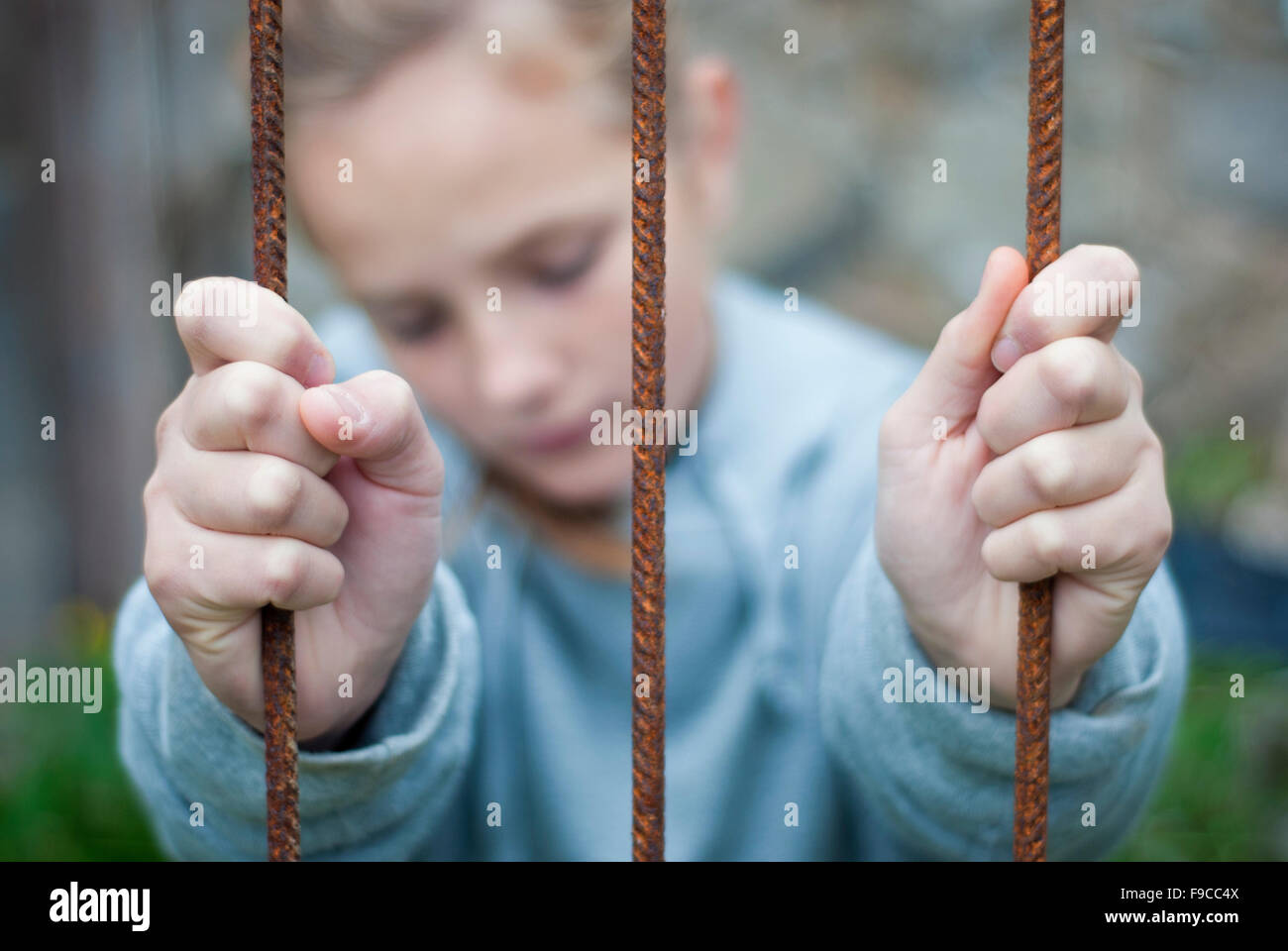 Sad lonely child is behind grid Stock Photo