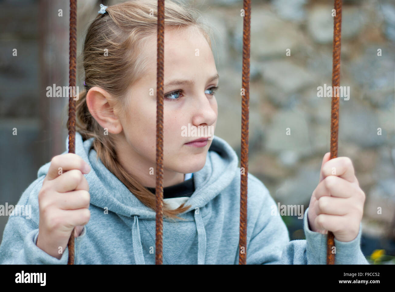 Sad lonely child is behind grid Stock Photo
