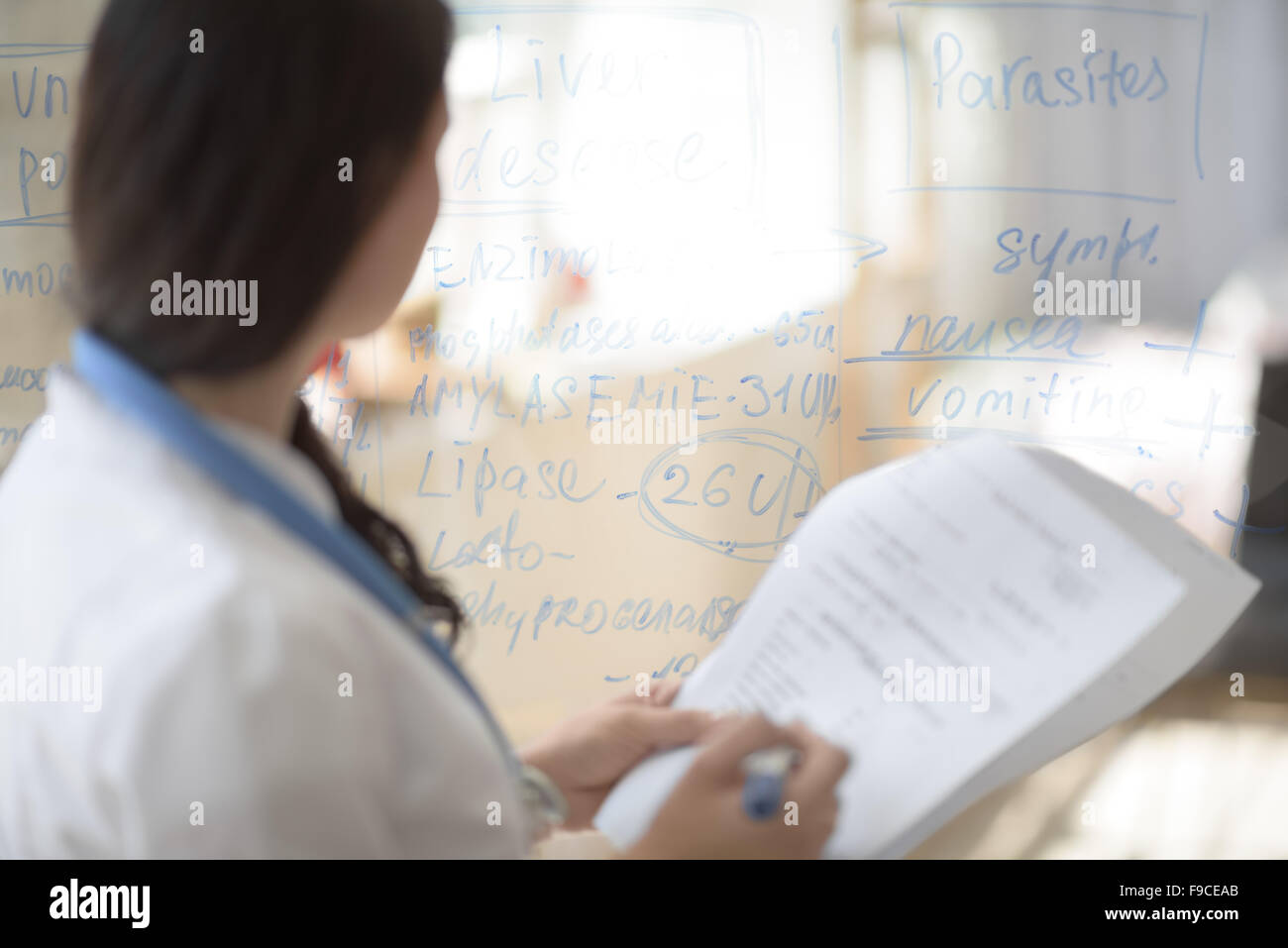 Medical doctor writing patient test results on transparent board to diagnose Stock Photo