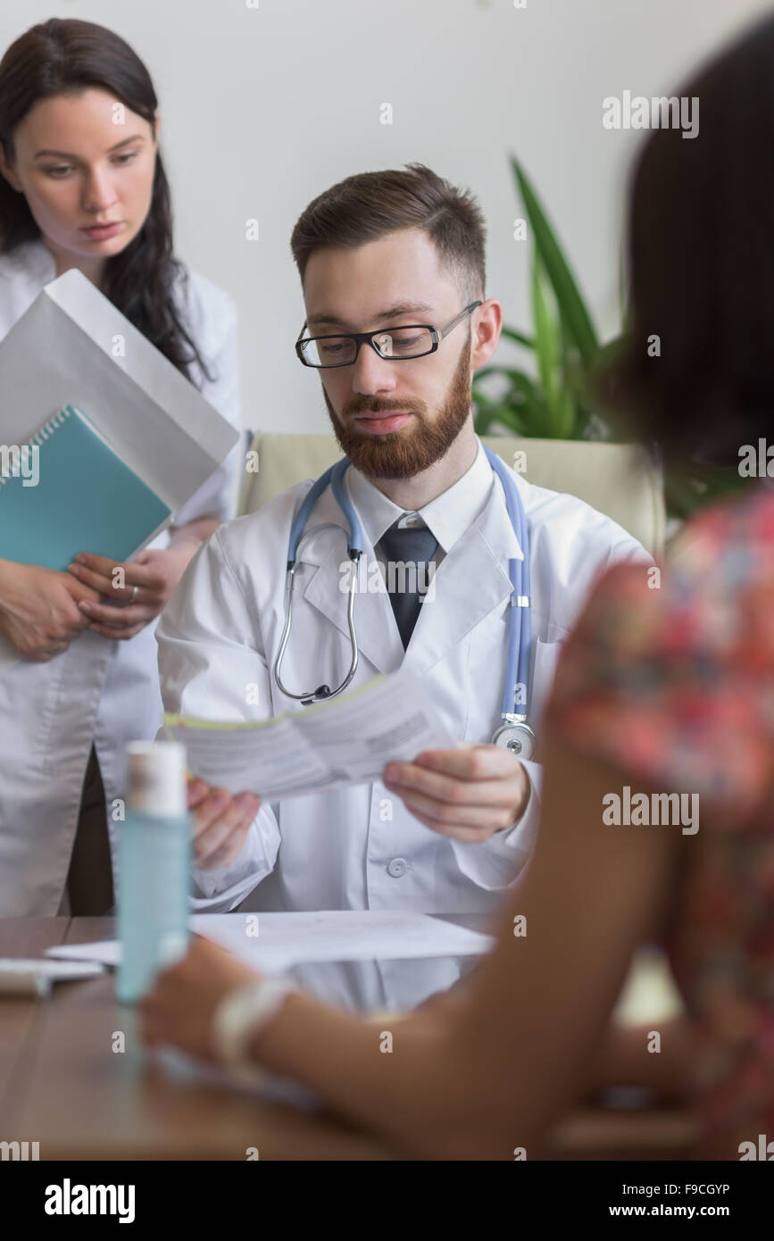 Confident practitioner consulting woman in hospital. Reading test results Stock Photo