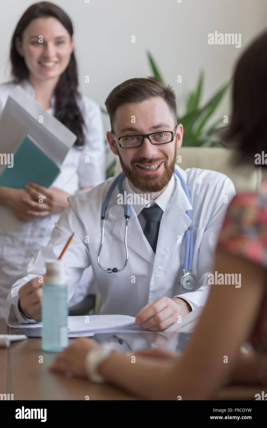 Confident practitioner consulting woman in hospital. Reading test results Stock Photo
