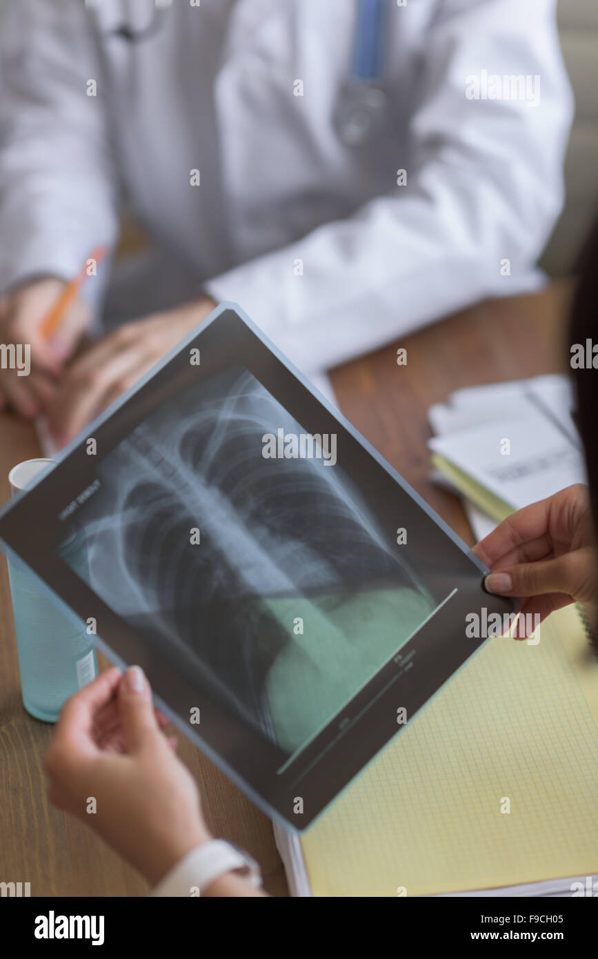 Confident practitioner consulting woman in hospital. Explaining results of chest x-ray scan Stock Photo