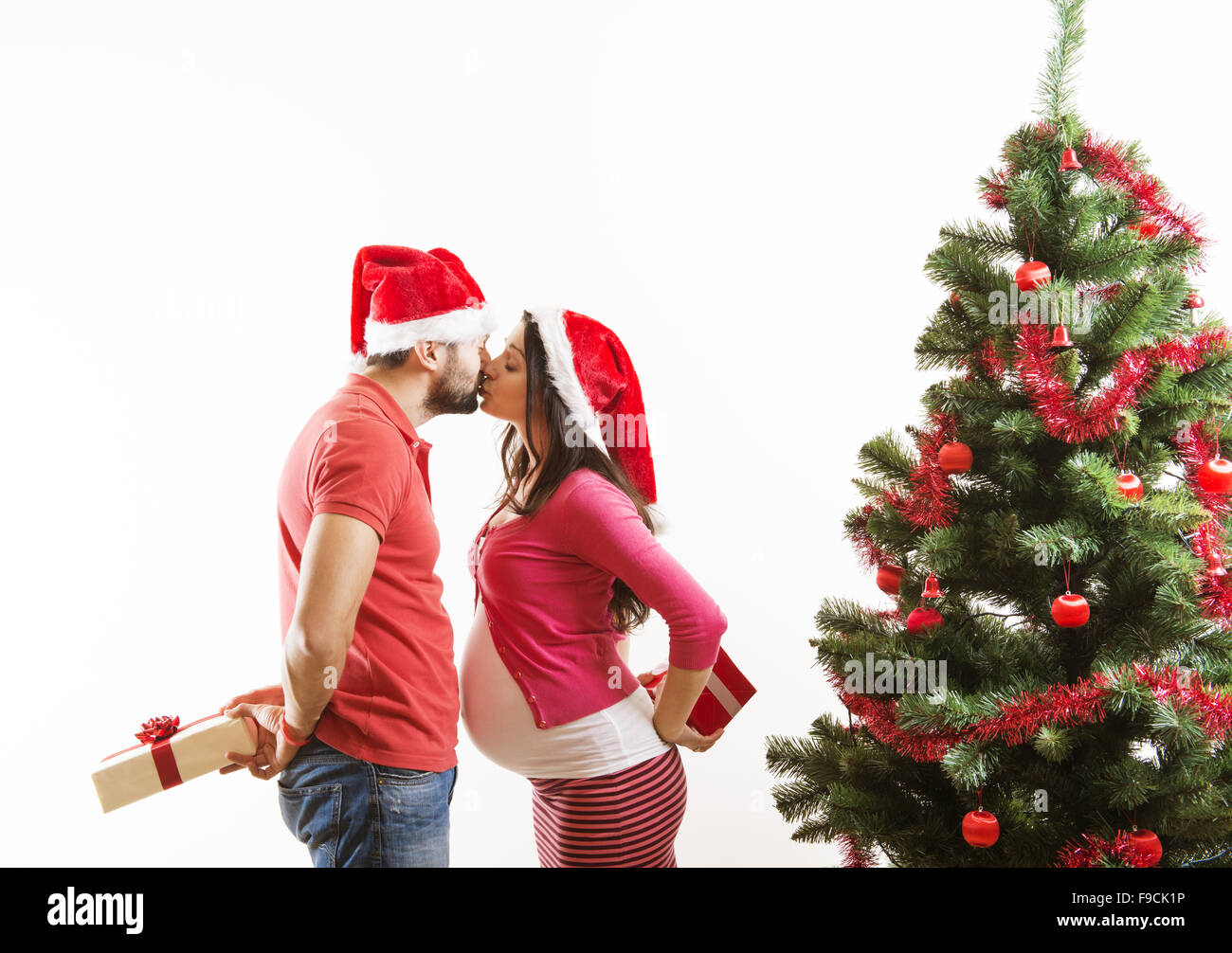 Young couple is dancing close to christmas tree. Woman is pregnant. Stock Photo