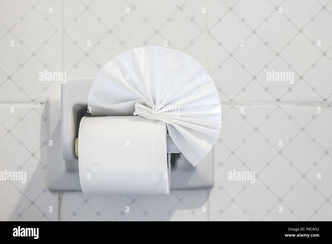 folded toilet paper on the wall with a toilet paper holder Stock Photo